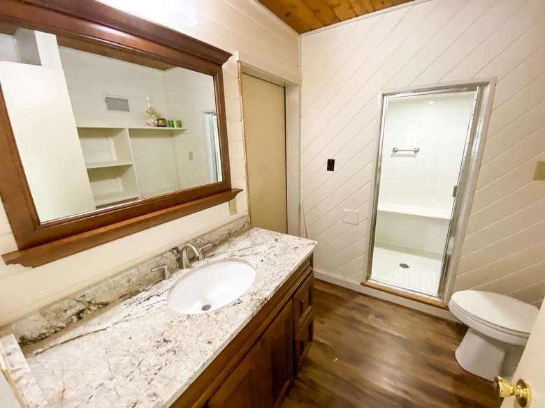 bathroom with a mirror, a sink, a toilet, and glass shower