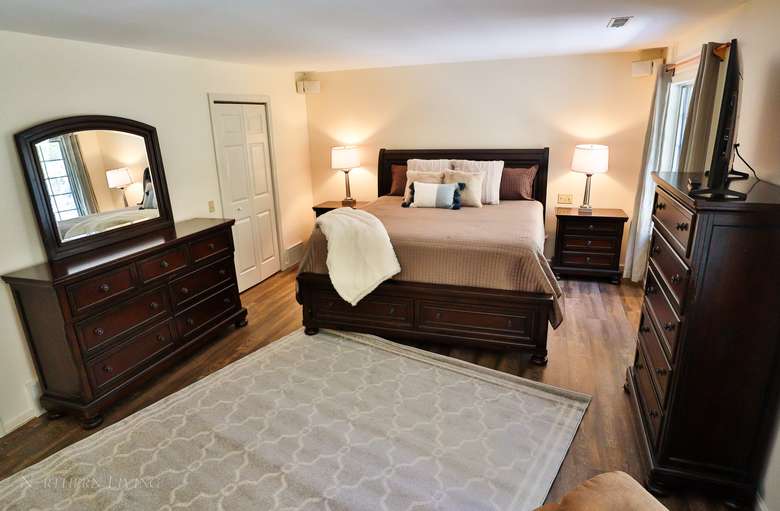Master Bedroom in a house with a bed, two dressers, a mirror, and two lamps