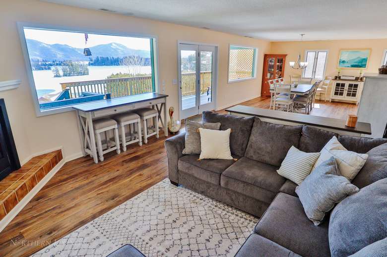 a living room with a gray couch and windows with views of the lake