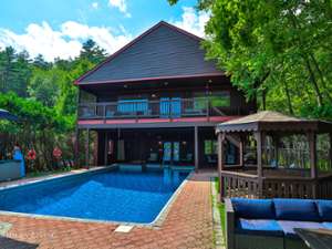 exterior of a brown house with a brown gazebo and an outdoor pool