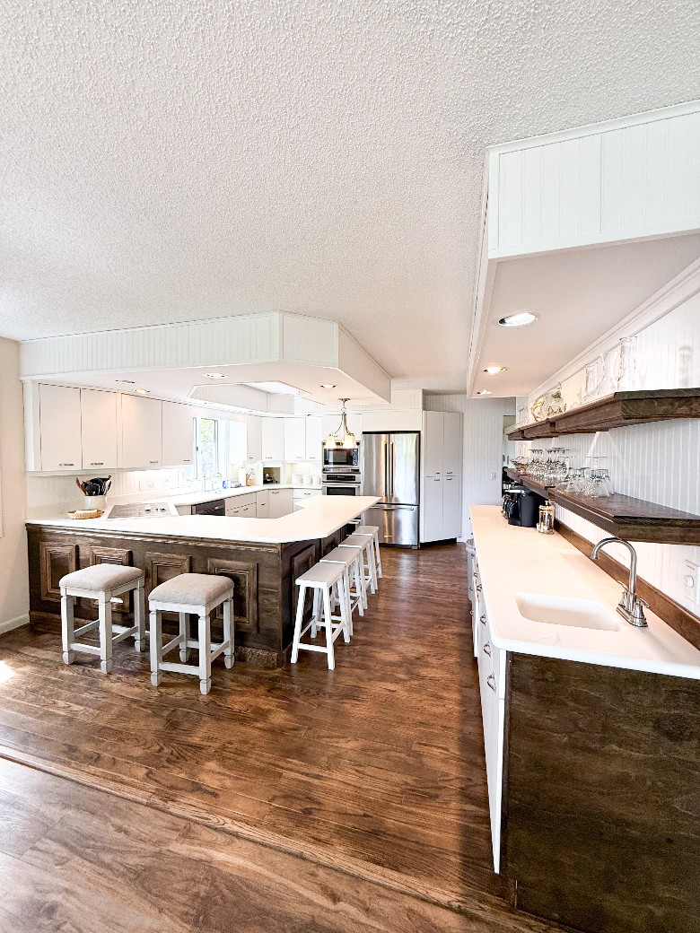 a kitchen with an island The second kitchen is very open with lots of natural light and has two ovens, a gas stove, and a bar with stools.