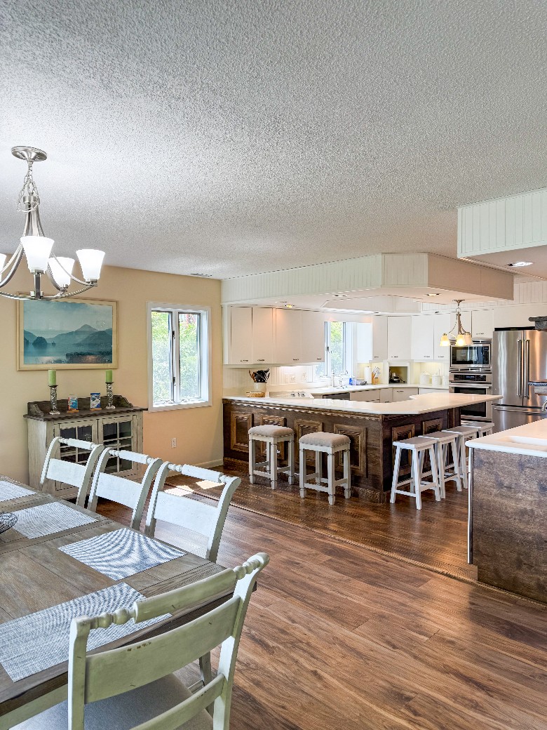 a kitchen with an island The second kitchen is very open with lots of natural light and has two ovens, a gas stove, and a bar with stools.