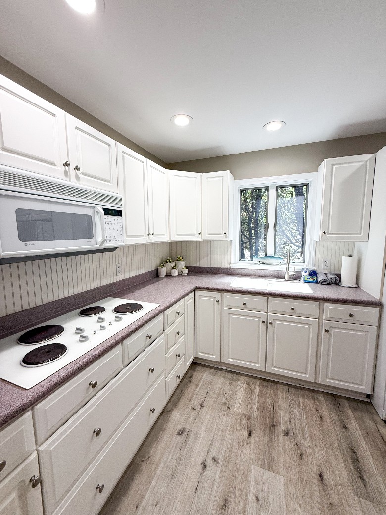 kitchen with white cabinets, a fridge, an oven, and a microwave ​Main level kitchen.