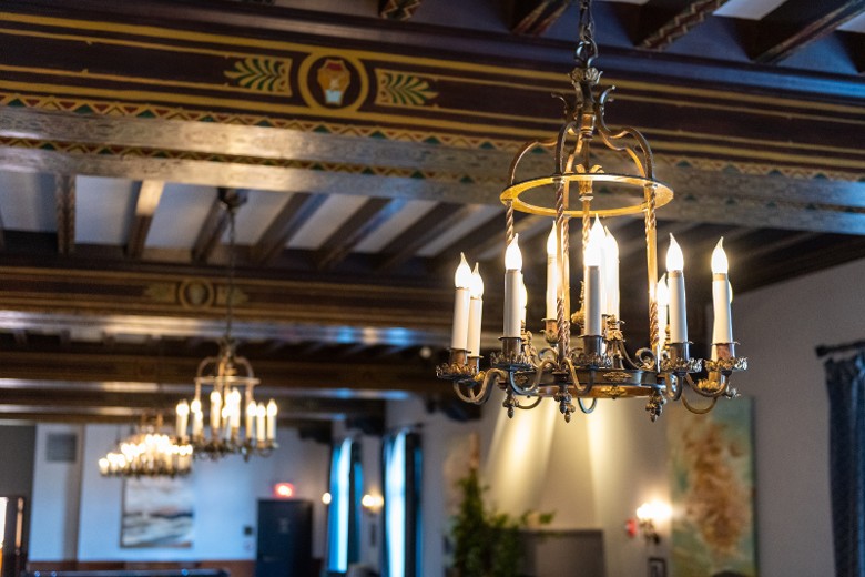 Close-up of chandeliers and hand-carved wood beams in the Great Hall at Hotel Saranac