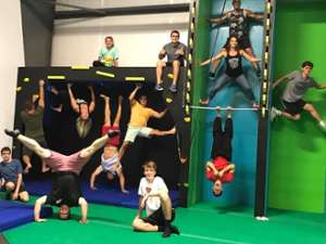 group of people on ninja obstacles in a gym