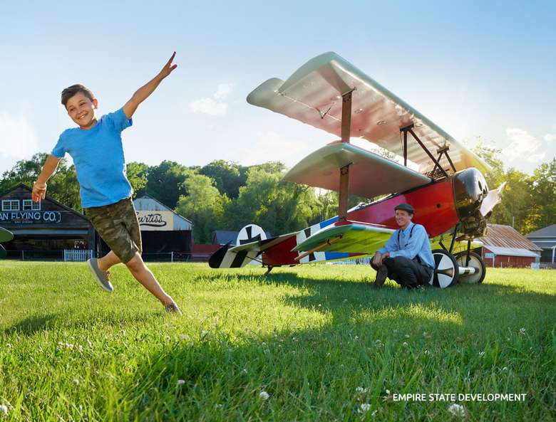airplane on ground and a boy running on grass