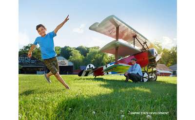 airplane on ground and a boy running on grass