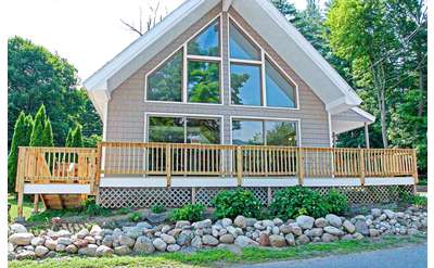 large house with wrap around deck and big glass windows