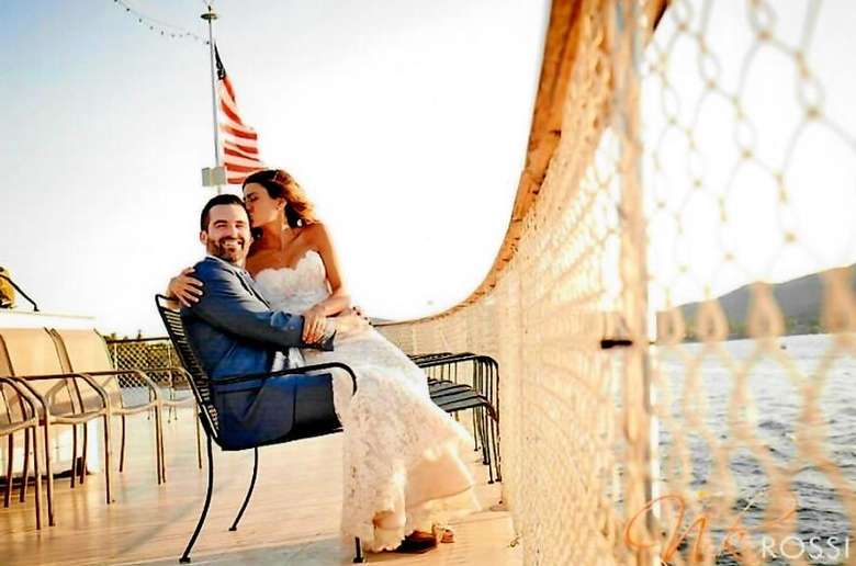 bride and groom smiling on the bow of a boat
