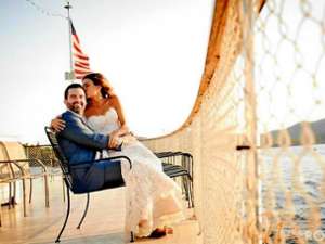 bride and groom smiling on the bow of a boat