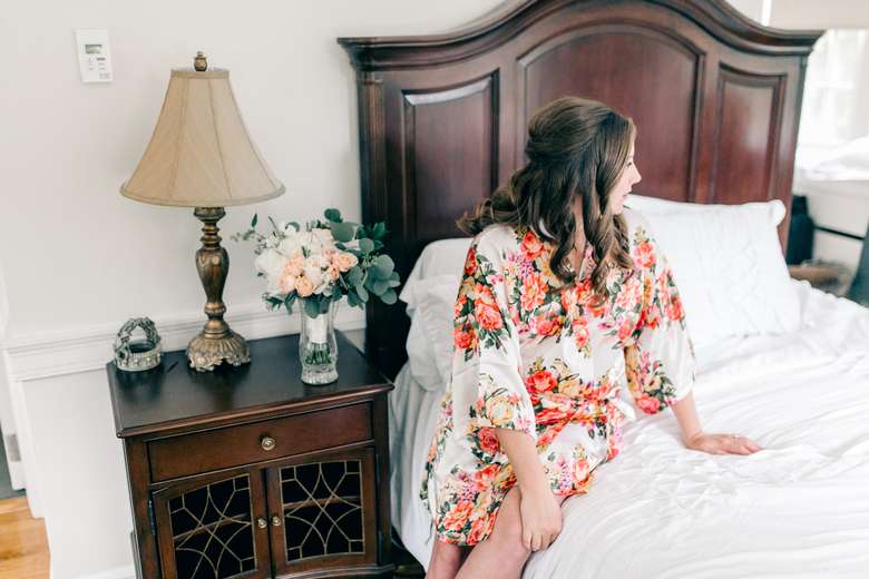 bride in a floral robe sitting on a bed