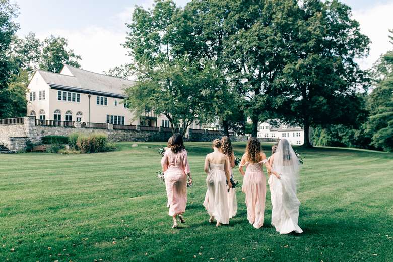 bride and bridesmaids walking on manicured lawn