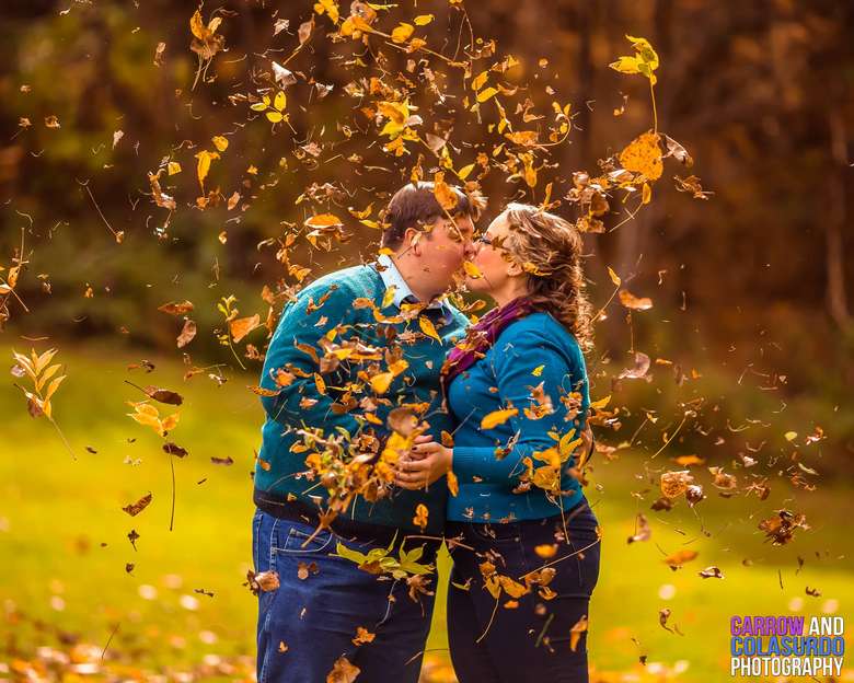 couple kissing with leaves blowing around them