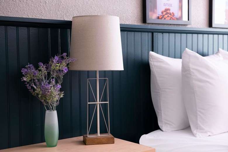 pillows on bed, a lamp and lavender on a nightstand