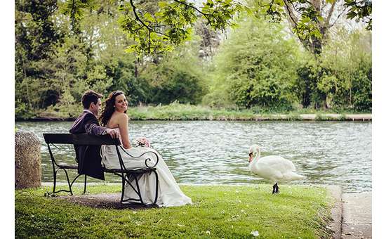 bride and groom seated on bench near a waterway