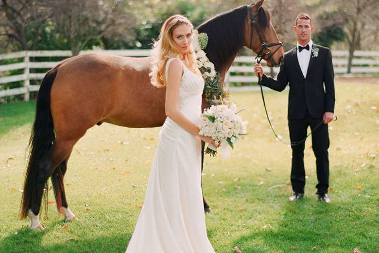 bride standing near horse that groom is holding