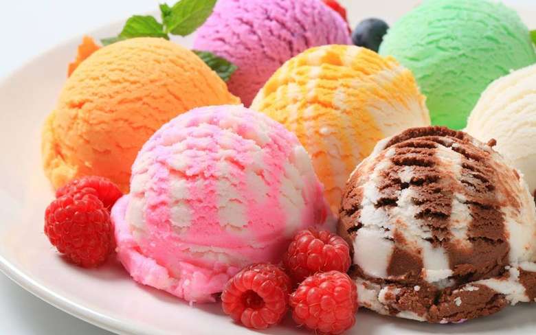 scoops of colorful ice cream with pieces of fruit around them