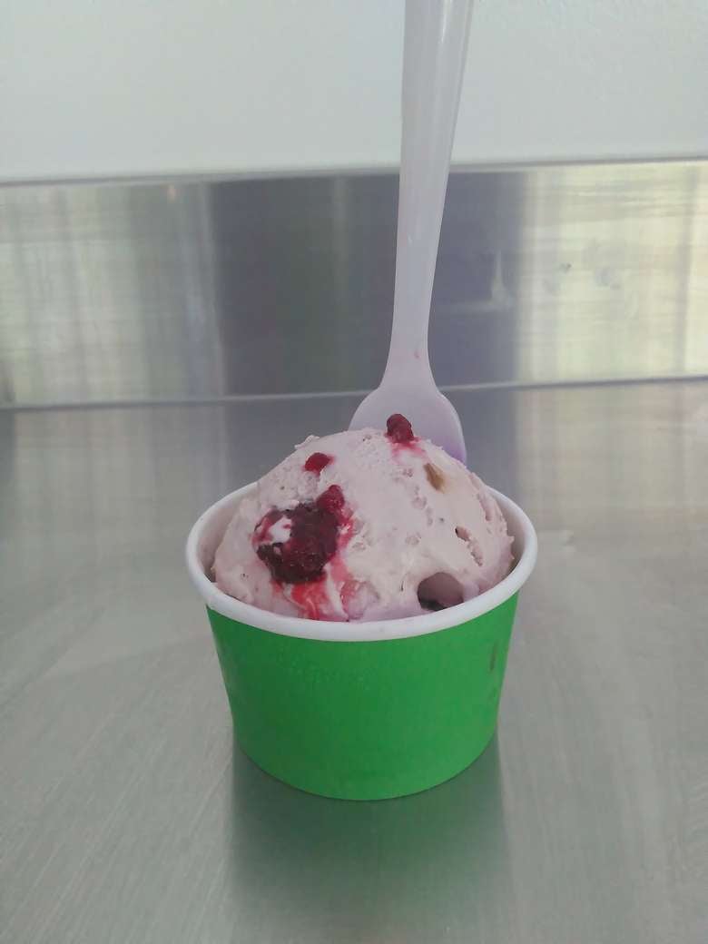 pink ice cream with red fruit in a green cup