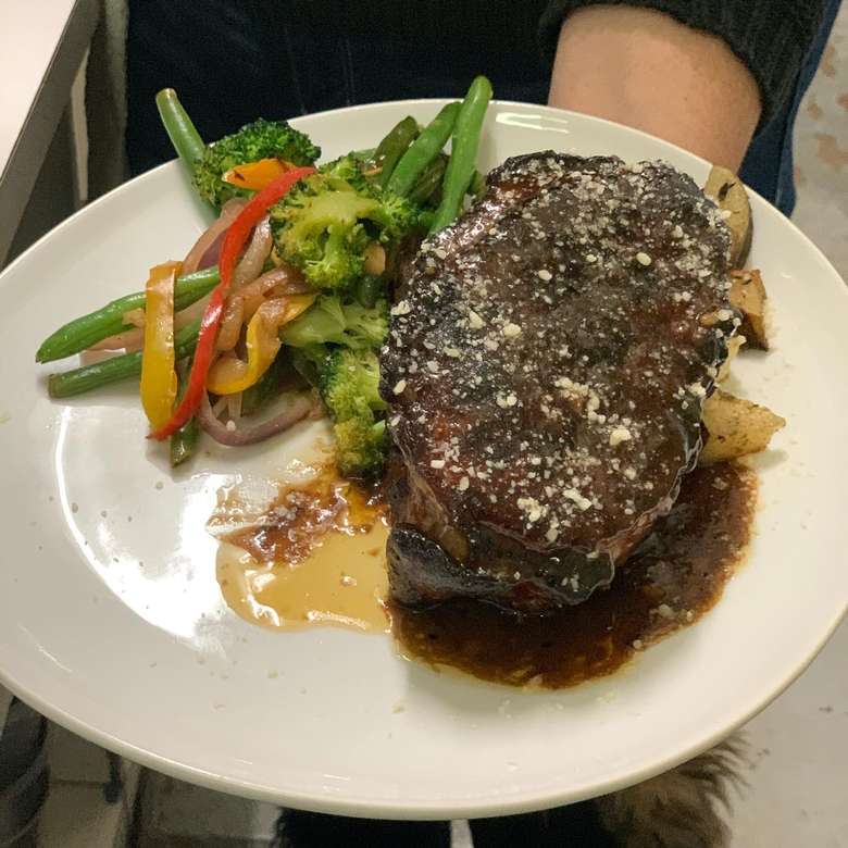 chef holding plate of steak and mixed vegetables