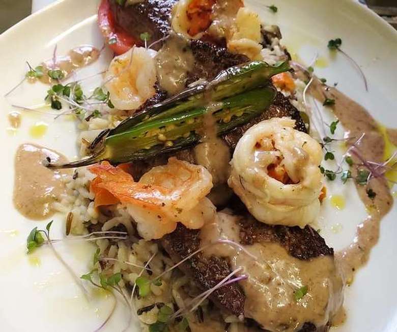 plated food with calamari, shrimp, peppers, and meat over rice.