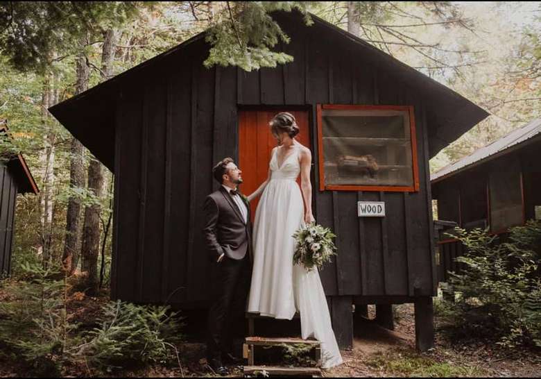bride and groom in front of cabin