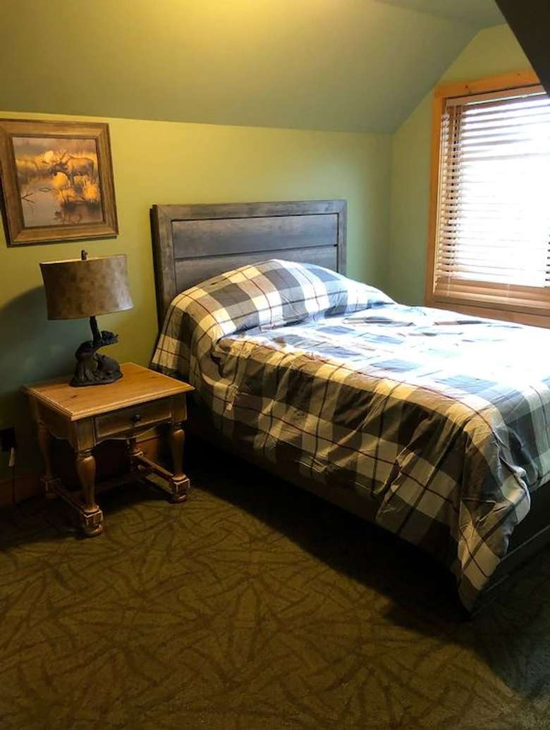 a bed with a nightstand and window nearby