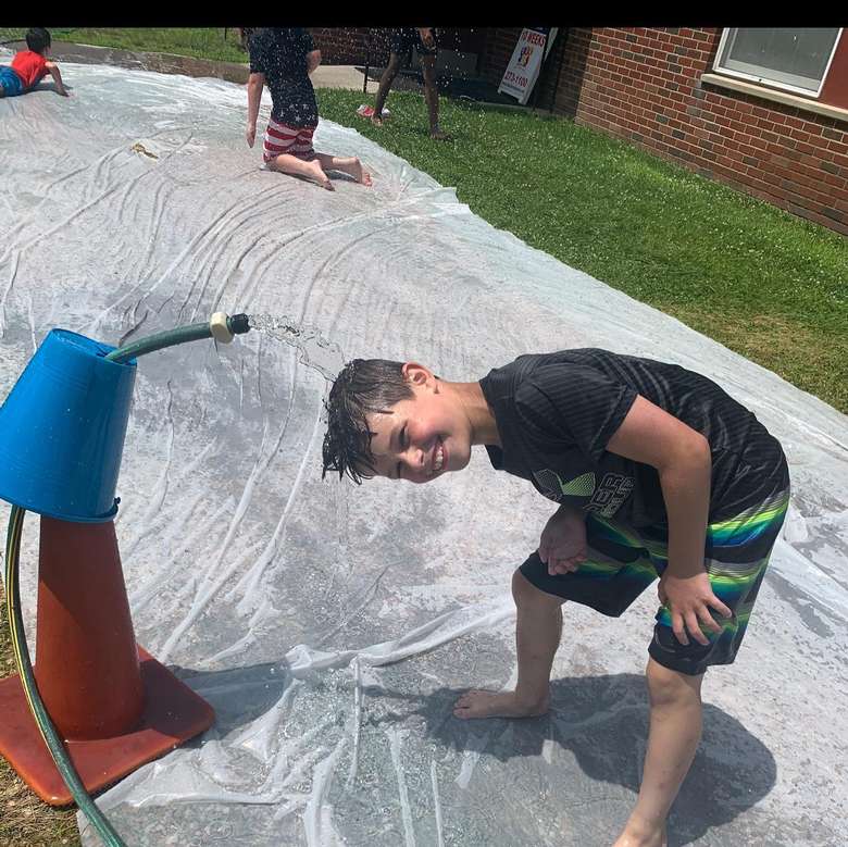 boy with head under sprinkler