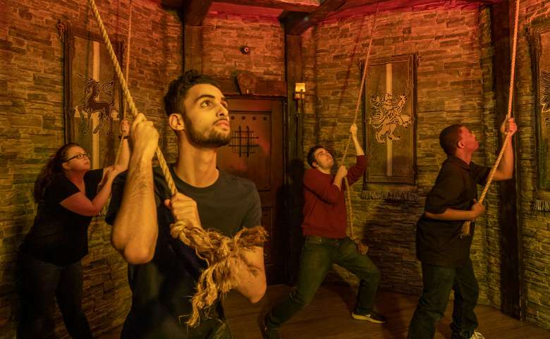 four people holding onto ropes in a medieval style room