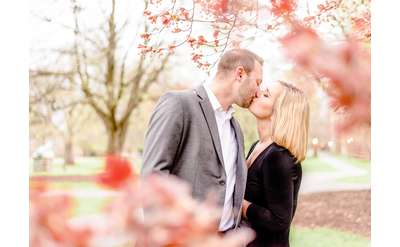 man and woman kissing outdoors near trees