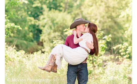man wearing cowboy hat holding up and kissing a woman