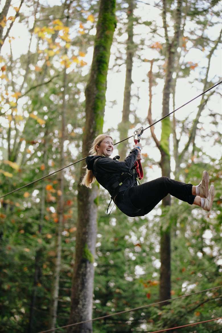 a woman ziplining through the trees