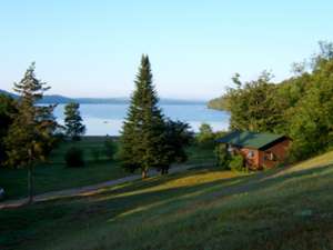 view of grassy lawn, a cabin, and a lake in the distance
