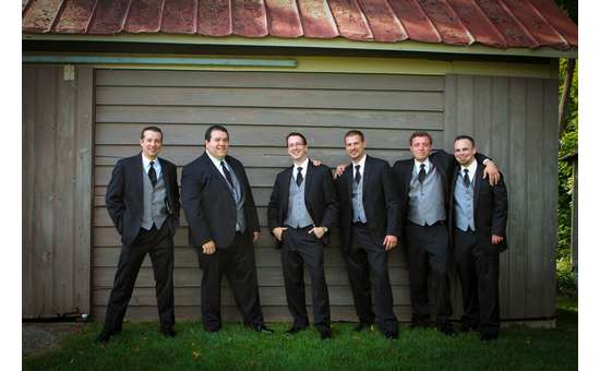 groom and groomsmen posing in front of a barn