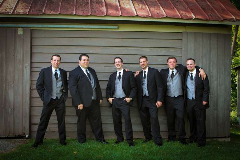 groom and groomsmen posing in front of a barn
