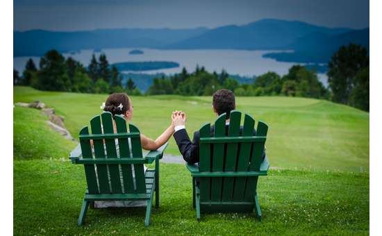 bride and groom in Adirondack chairs holding hands, looking out at mountains