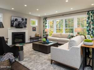 a spacious living room with white couches and colorful green decor