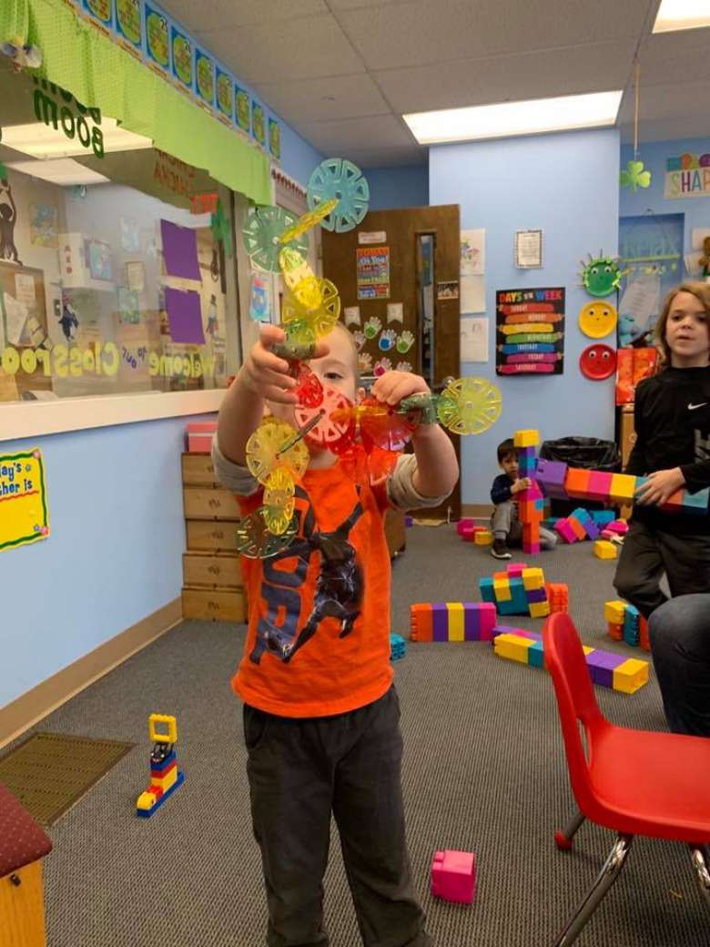 kid in nursery school holds up toy