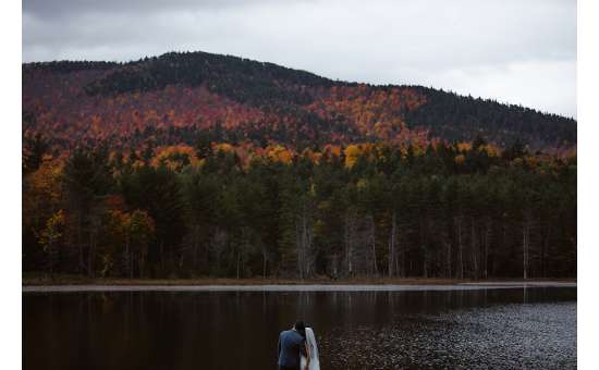 Couple on private lake along the mountains in the Adirondacks - Photo by Avonture Elopements