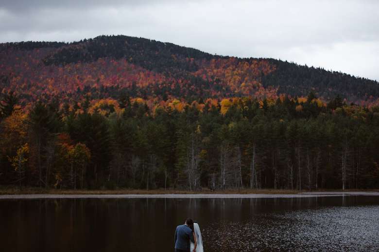 Couple on private lake along the mountains in the Adirondacks - Photo by Avonture Elopements