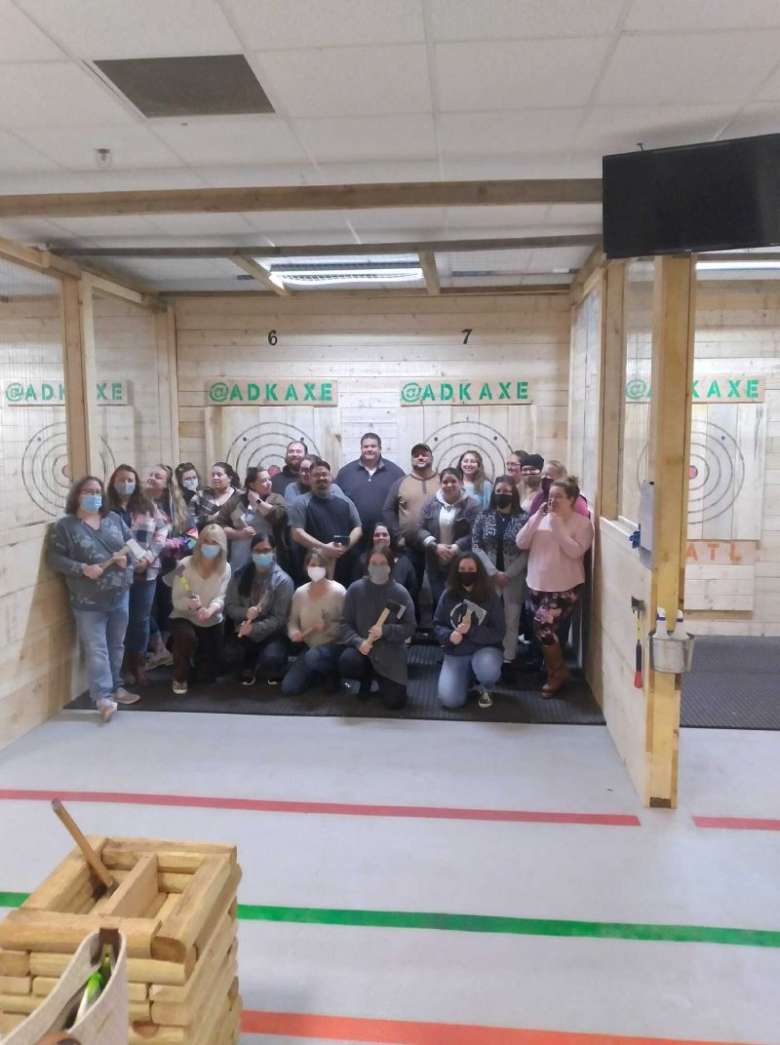 group of people standing in front of axe throwing boards