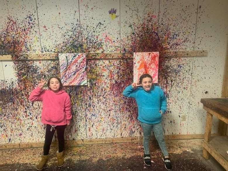 two girls standing in front of wall with sprayed paint