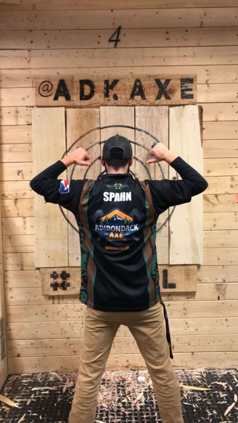 back view of man standing in front of axe throwing board