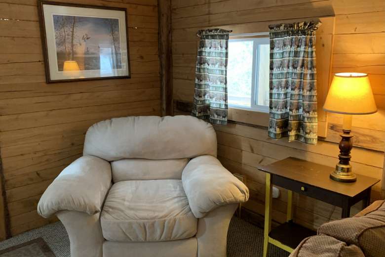cabin living room with a window and a white chair