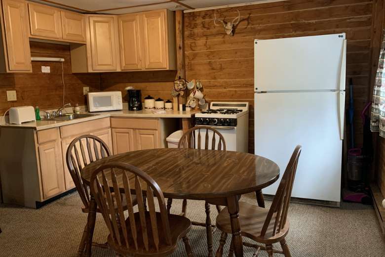 cabin kitchen with a fridge, table, chairs, and appliances on the counters