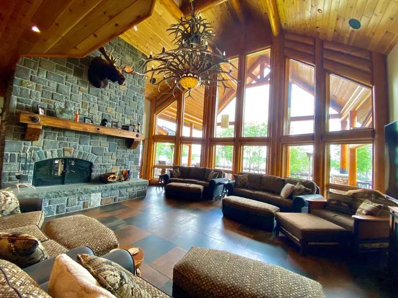 inside of a spacious living room with tall windows and a stone fireplace