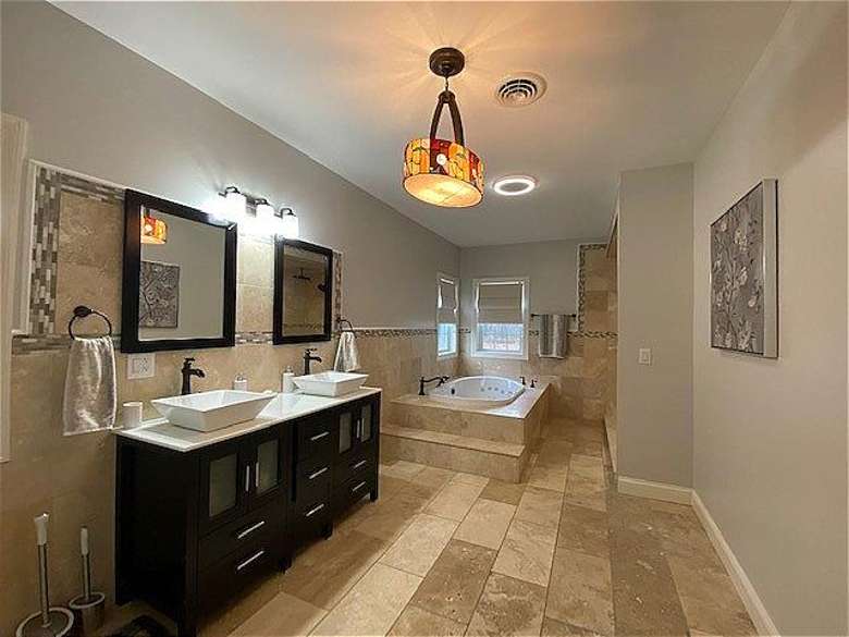 Large master bathroom with double vanity, rain head shower system with enclosure, and jacuzzi. There is also a large walk in closet inside the master bathroom.