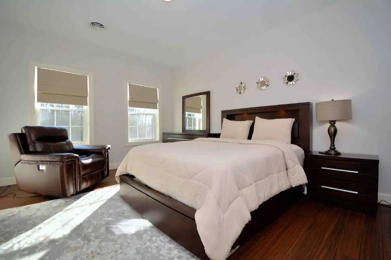 One of the 9 bedrooms is pictured here with a bed, brown chair, windows, and cabinets