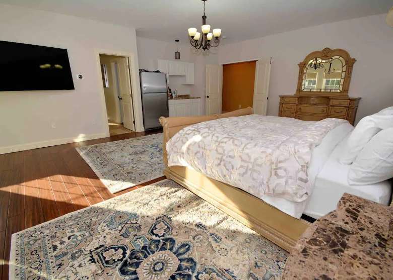 Large bedroom with kitchenette with a king size bed, 65-inch Smart TV, Sonos, dresser, and 2 night stands.