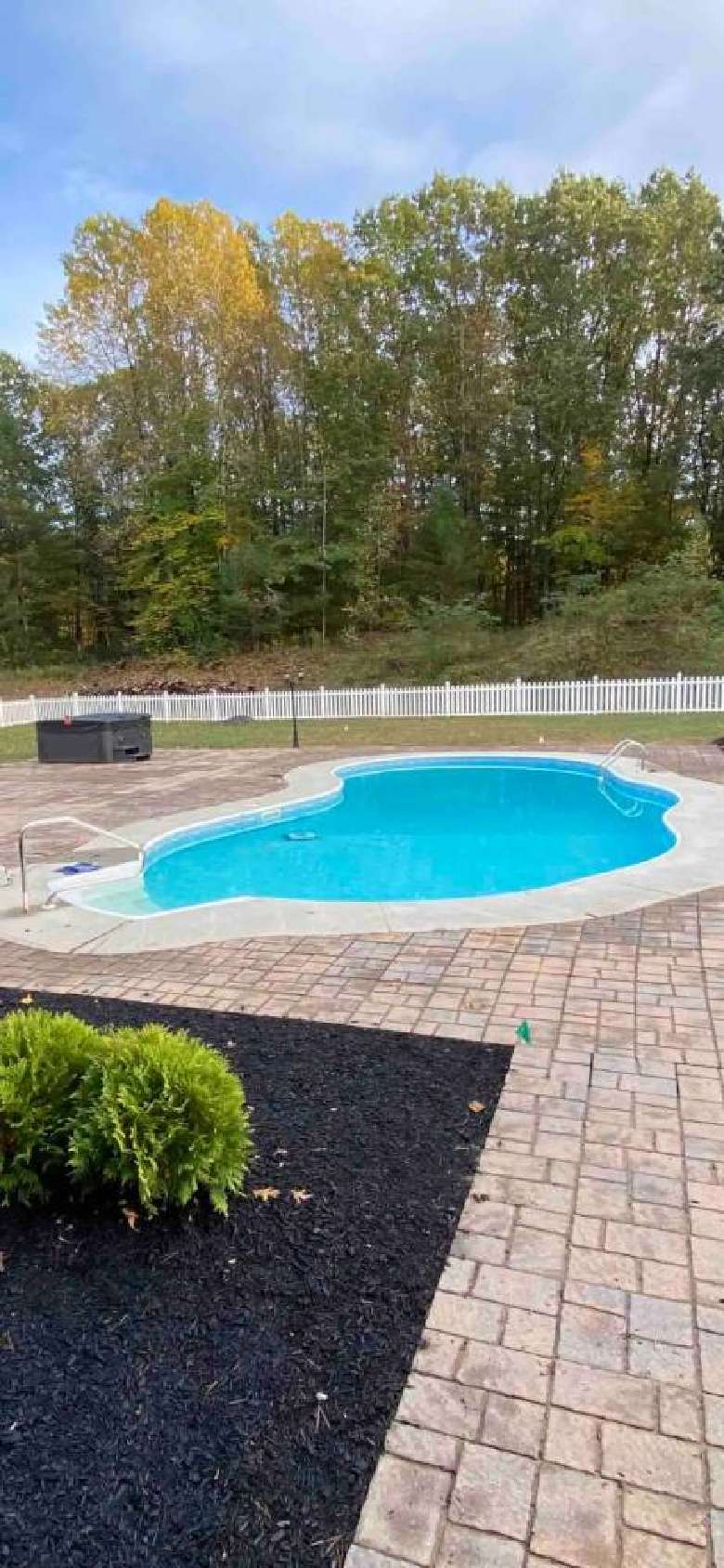 An in ground heated pool and hot tub with large fenced in backyard