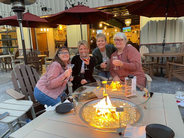 A group of ladies enjoying drinks by the fire pit